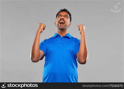 success, emotion and expression concept - happy young indian man celebrating victory over grey background. indian man celebrating victory