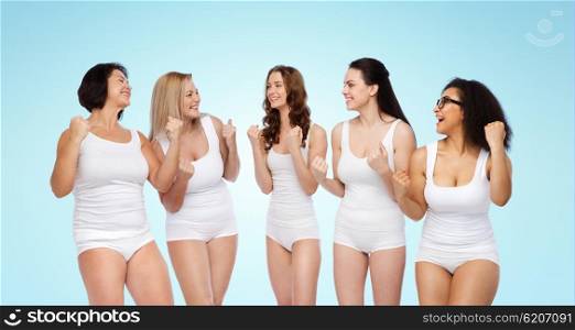 success, friendship, beauty, body positive and people concept - group of happy different women in white underwear celebrating victory over blue background