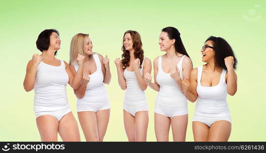 success, friendship, beauty, body positive and people concept - group of happy different women in white underwear celebrating victory over green natural background