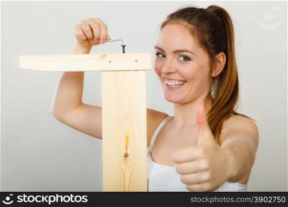 Success ful woman assembling furniture. DIY.. Successful soman assembling wooden furniture using hex key. DIY enthusiast. Young girl with thumb up doing home improvement.