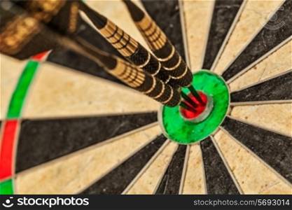 Success hitting target aim goal achievement concept background - three darts in bull&#39;s eye close up