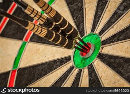 Success hitting target aim goal achievement concept background - three darts in bull&#39;s eye close up