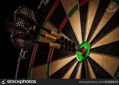 Success hitting target aim goal achievement concept background - three darts in bull&rsquo;s eye close up