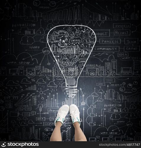 Success idea. Top view of girl in sport shoes standing on blackboard