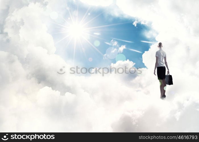 Success in business. Back view of businesswoman standing on cloud high in sky