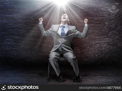 Success in business. Emotional businessman sitting on chair and screaming ahead