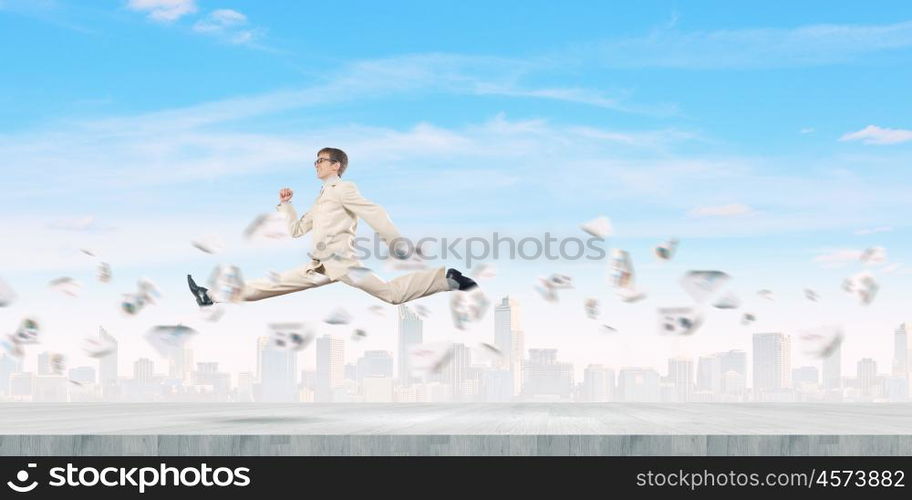 Success in business. Young cheerful businessman in jump against city background