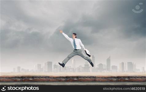 Success in business. Young cheerful businessman in jump against city background