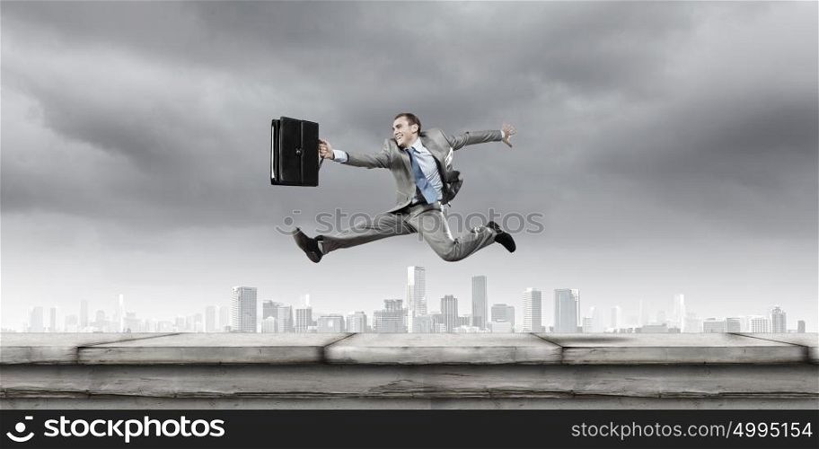 Success in business. Young cheerful businessman in jump against city background