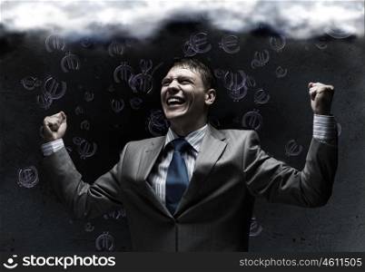 Success in business. Young joyful businessman with hands up celebrating success