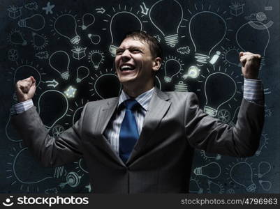 Success in business. Young joyful businessman with hands up celebrating success