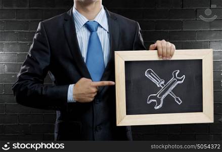 Success of sales. Unrecognizable businessman holding chalkboard with tools for success concept