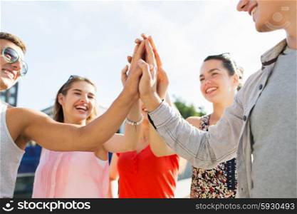 success, people, teamwork and gesture concept - close up of happy friends hands making high five outdoors