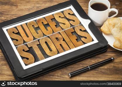 success stories typography - word abstract in vintage letterpress wood type on a digital tablet with a cup of coffee