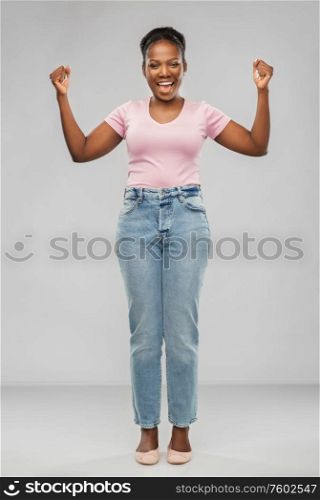 success, winning gesture and people concept - happy young african american woman celebrating victory over grey background. happy african american woman celebrating success