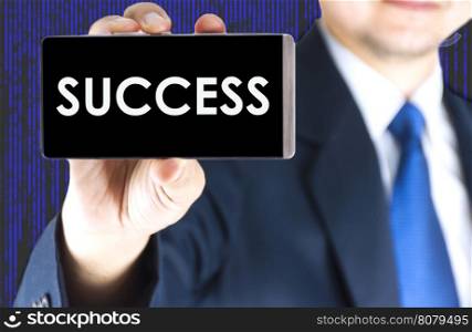SUCCESS word on mobile phone screen in blurred young businessman hand and digital technology background, business concept