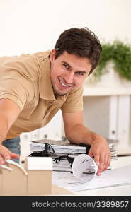 Successful architect man working at office with plans and architectural model