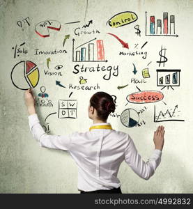 Successful business strategy plan. Businesswoman standing with back drawing business ideas on wall