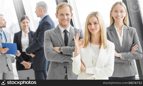 Successful business team. Successful business team with arms crossed at the office, woman showing ok sign