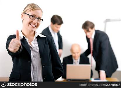 Successful business woman standing in front of her colleagues; selective focus on woman