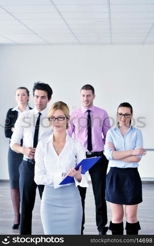 Successful business woman standing with her staff in background at modern bright office