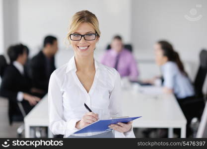 Successful business woman standing with her staff in background at modern bright office