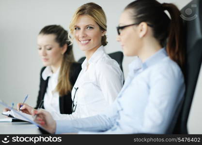 Successful business woman standing with her staff in background at modern bright office