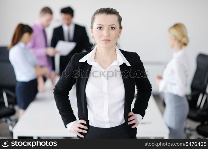 Successful business woman standing with her staff in background at modern bright office