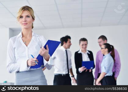 Successful business woman standing with her staff in background at modern bright office