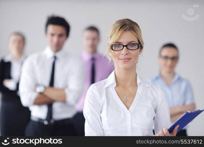 Successful business woman standing with her staff in background at modern bright office