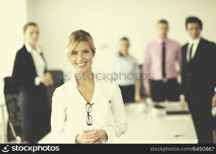 Successful business woman standing with her staff in background at modern bright office