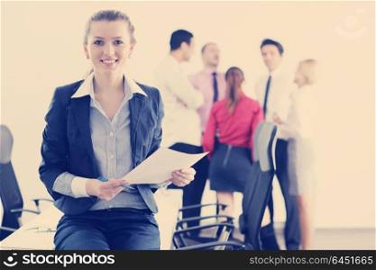 Successful business woman standing with her staff in background at modern bright office