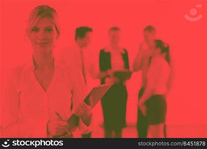 Successful business woman standing with her staff in background at modern bright office