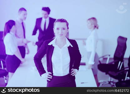 Successful business woman standing with her staff in background at modern bright office