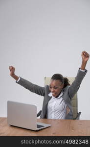 Successful business woman with arms up sitting in front of laptop at office