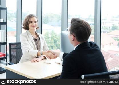Successful businessman and businesswoman happy and shake hands after meeting for partnership in modern office