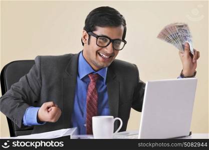Successful businessman holding banknotes at desk