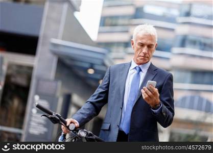 Successful businessman on bicycle with mobile phone. Successful businessman on bicycle in city holding mobile phone