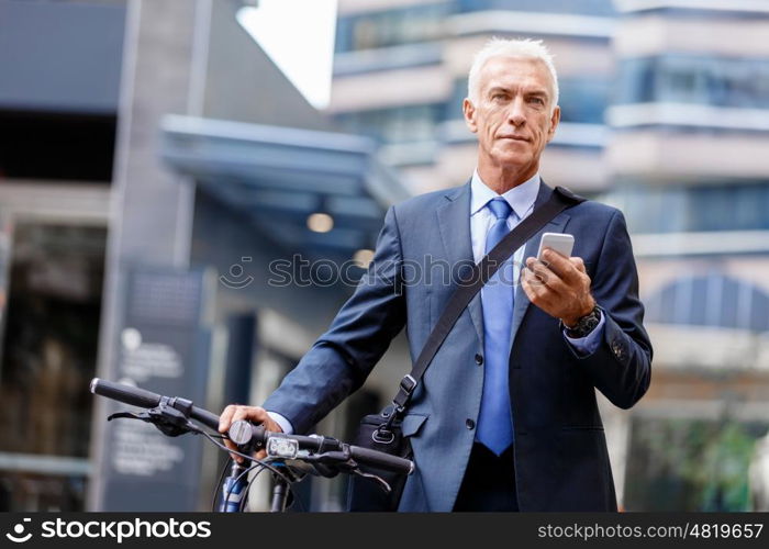 Successful businessman on bicycle with mobile phone. Successful businessman on bicycle in city holding mobile phone