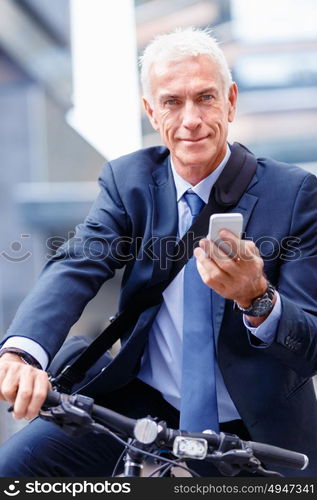 Successful businessman on bicycle with mobile phone. Successful businessman on bicycle in city holding mobile phone