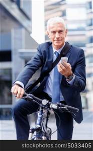 Successful businessman on bicycle with mobile phone. Successful businessman on bicycle in city holding mobile phone