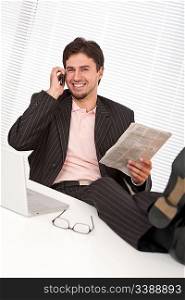 Successful businessman on the phone with legs up