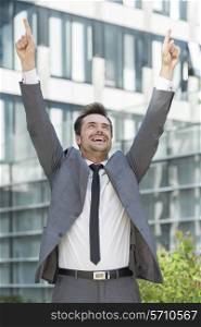 Successful businessman pointing upwards outside office building