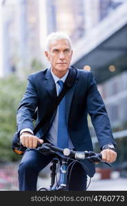 Successful businessman riding bicycle. Successful businessman in suit riding bicycle