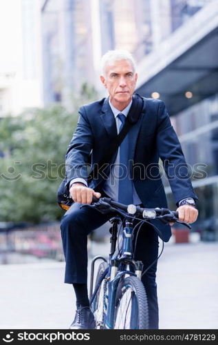 Successful businessman riding bicycle. Successful businessman in suit riding bicycle