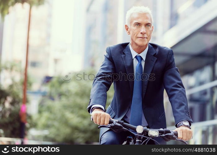 Successful businessman riding bicycle. Successful businessman in suit riding bicycle