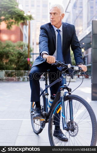 Successful businessman riding bicycle. Successful businessman in suit riding bicycle