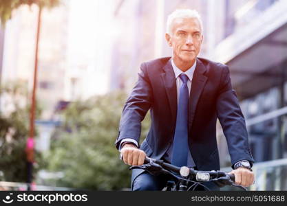 Successful businessman riding bicycle. Successful businessman in suit riding bicycle