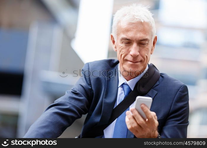 Successful businessman riding bicycle. Successful businessman in suit riding bicycle and holding mobile phone