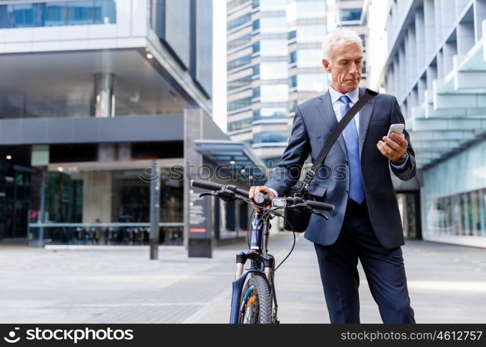 Successful businessman riding bicycle. Successful businessman in suit riding bicycle and holding mobile phone